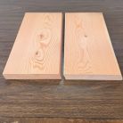 Two light wooden planks placed side by side on a dark wooden table, showing wood grain and knots.
