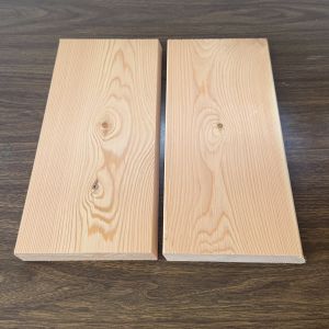 Kiln Dried Canadian Douglas Fir Cladding Boards | Rainscreen Two light wooden planks laid side by side with a narrow gap on a dark wood surface.