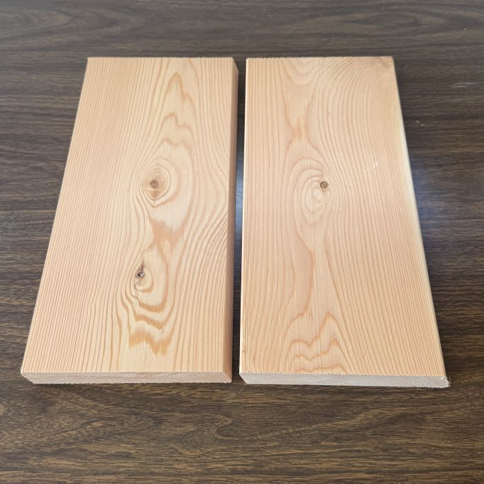 Two light wooden planks laid side by side with a narrow gap on a dark wood surface.